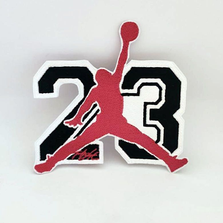 Toppa ricamata con sagoma giocatore basket di colore rosso che salta ed esegue una schiacciata con numero 23 in secondo piano nero con contorno bianco su sfondo bianco