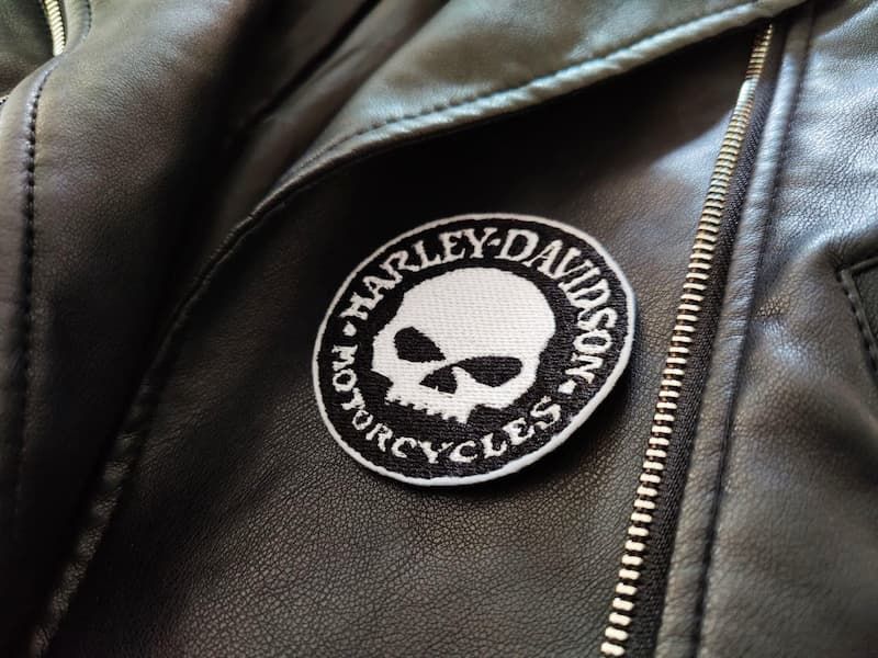 Fotografia di un dettaglio di un giubbotto di pelle nero con toppa rotonda nera con teschio e scritta Harley-Davidson Motorcycles