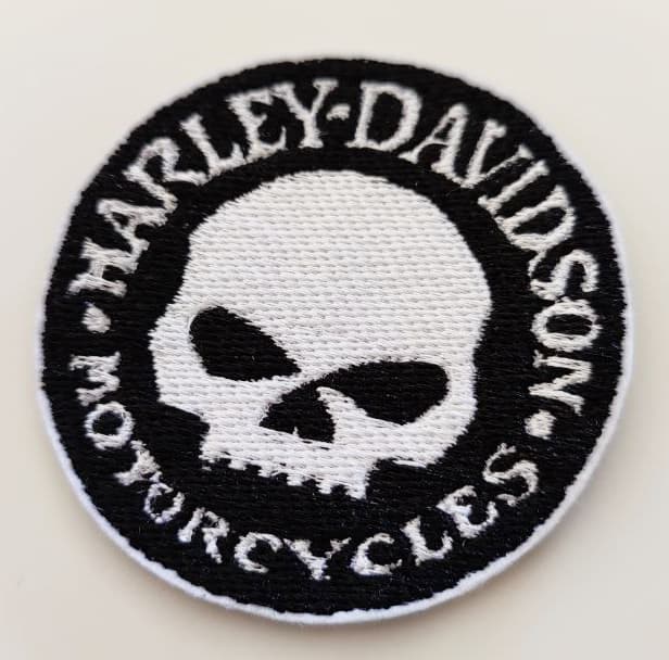 Fotografia toppa rotonda nera con testa teschio al centro e scritta sul contorno in stampatello bianco Harley-Davidson Motorcycles