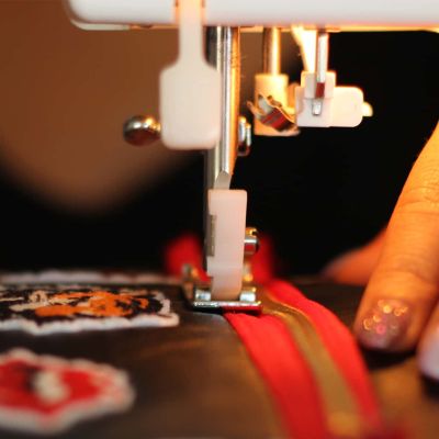 Fase di cucitura artigianale di una patch con logo ricamato su una felpa personalizzata