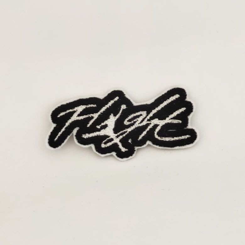 Toppa ricamata della parola "Flight" bianca con contorno nero ed al posto della lettera i c'è la sagoma di Michael Jordan che schiaccia a canestro